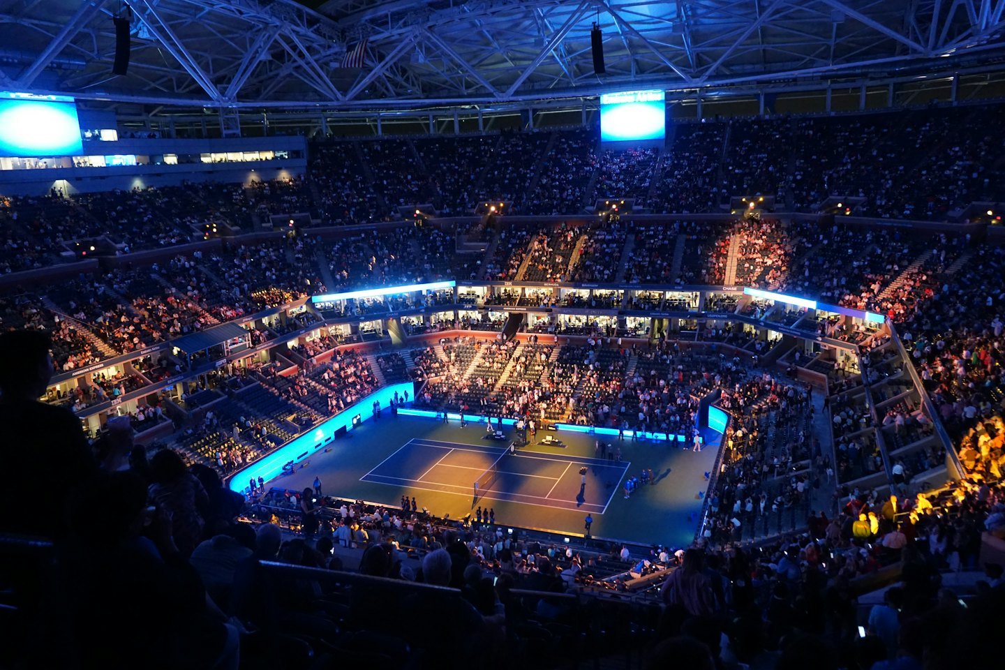 Thousands of spectators fill a large stadium for a tennis match.