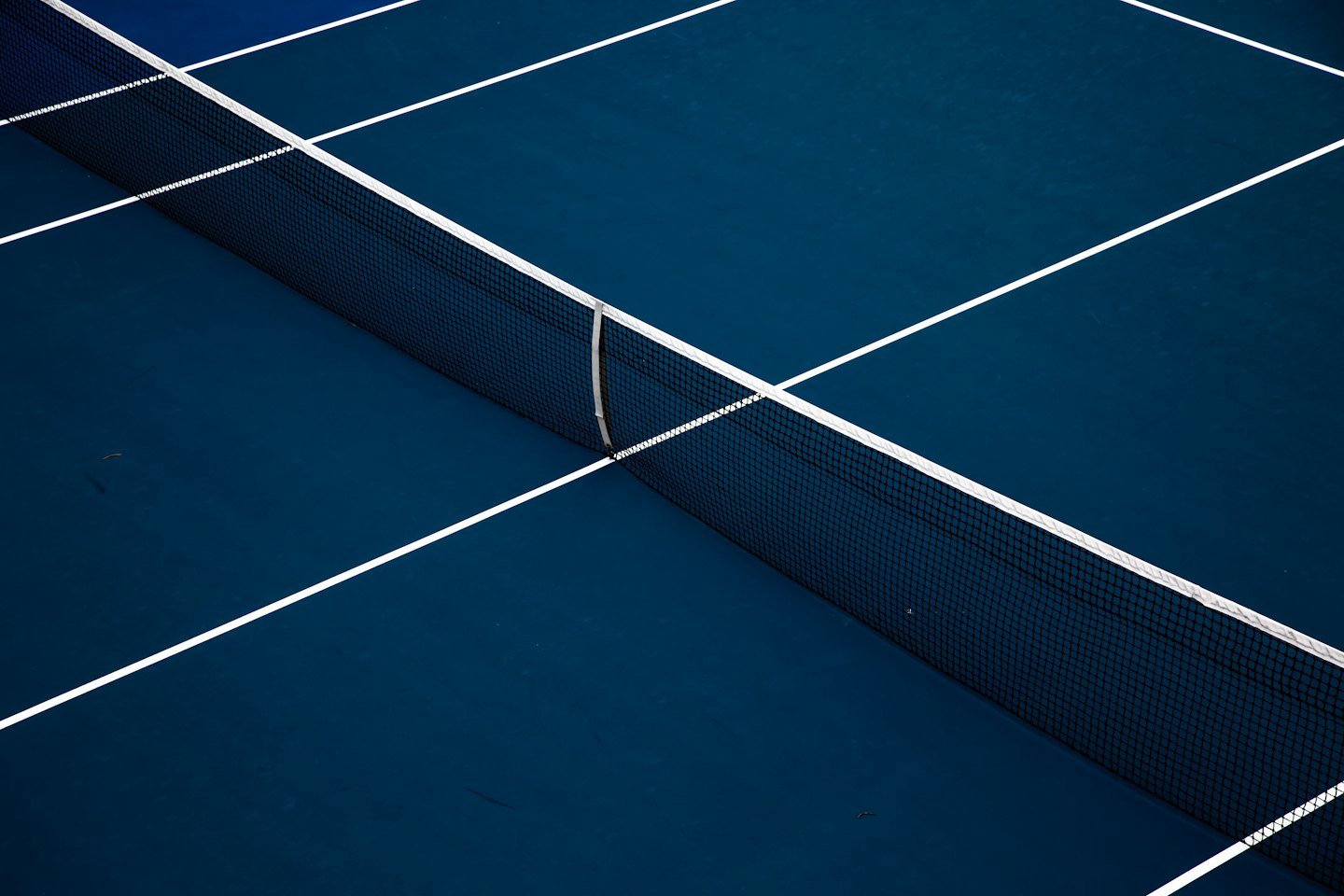 A blue tennis court with white lines and a net.