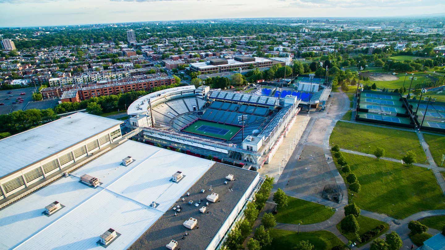 A large tennis complex surrounded by a dense residential cityscape.